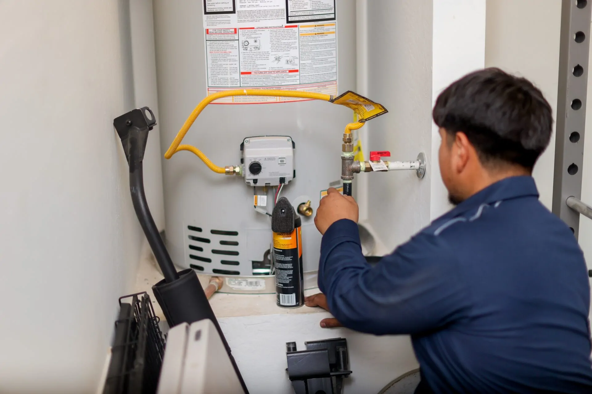 Canilu Air technician servicing a tank water heater as part of summer plumbing repairs in AZ