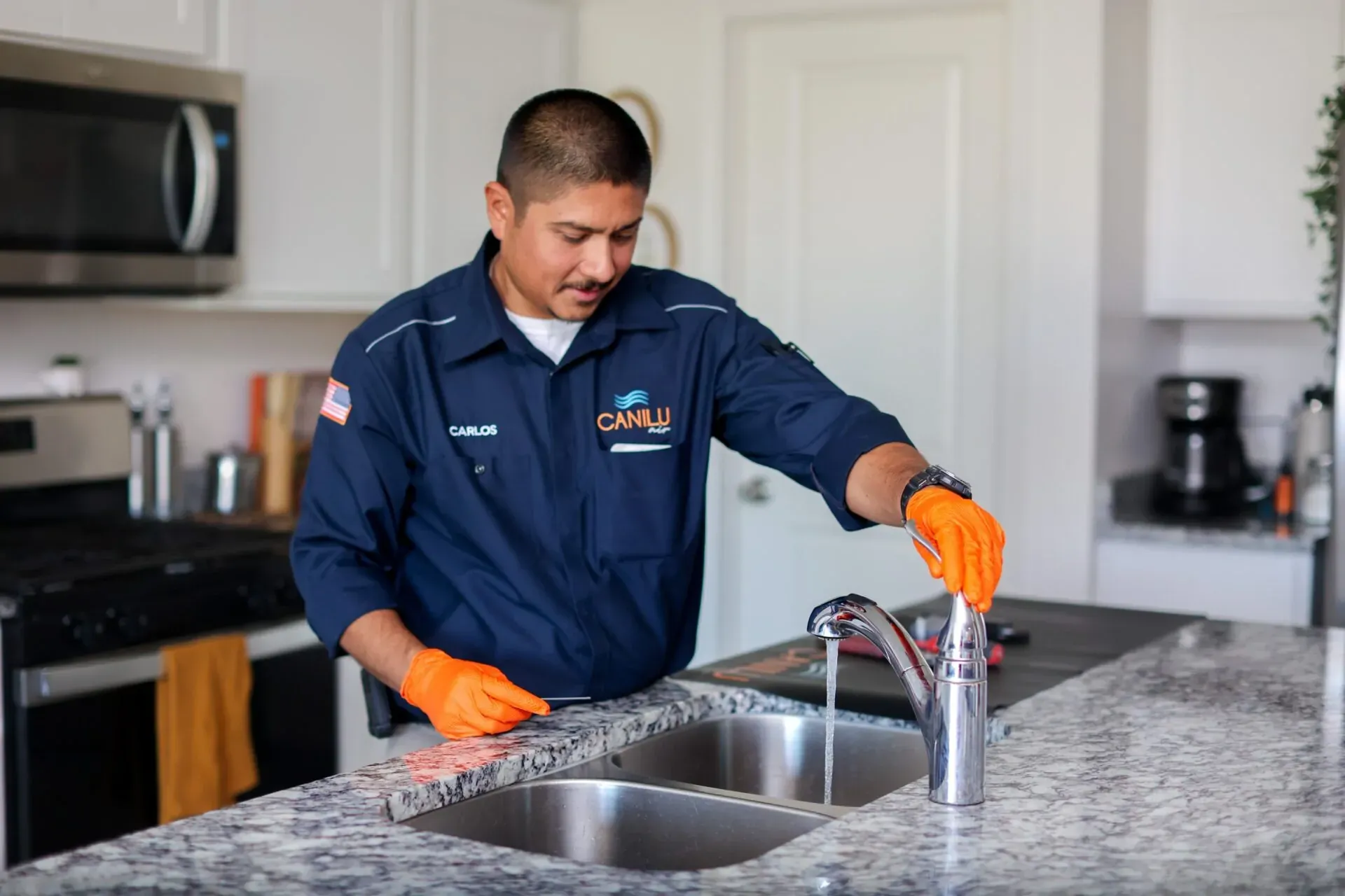 Canilu Air technician inspecting a kitchen faucet for hard water and Phoenix plumbing issues