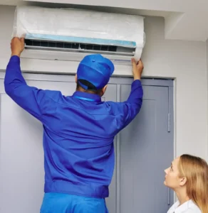 Technician performing an AC installation Phoenix homeowner watches complete on a wall-mounted unit