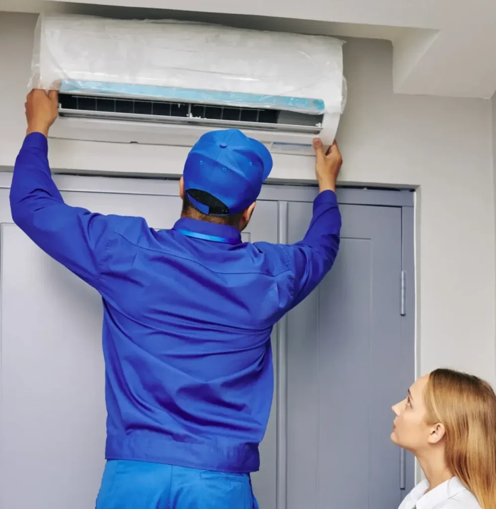Technician performing an AC installation Phoenix homeowner watches complete on a wall-mounted unit